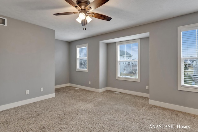 spare room with ceiling fan, visible vents, baseboards, and light colored carpet