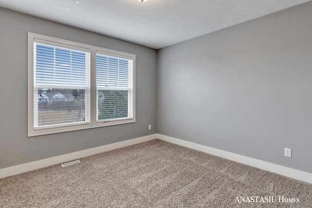 empty room featuring carpet floors, baseboards, and visible vents