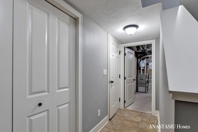 hall featuring a textured ceiling and baseboards