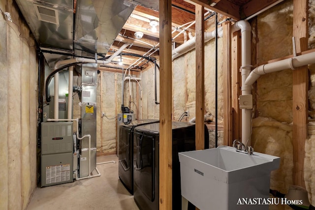 unfinished below grade area featuring independent washer and dryer, visible vents, a sink, and heating unit