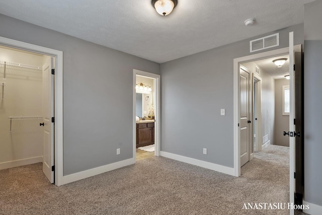 unfurnished bedroom with carpet floors, visible vents, a spacious closet, and a textured ceiling