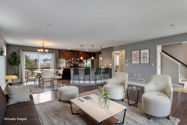 living room with visible vents, stairway, wood finished floors, a notable chandelier, and recessed lighting