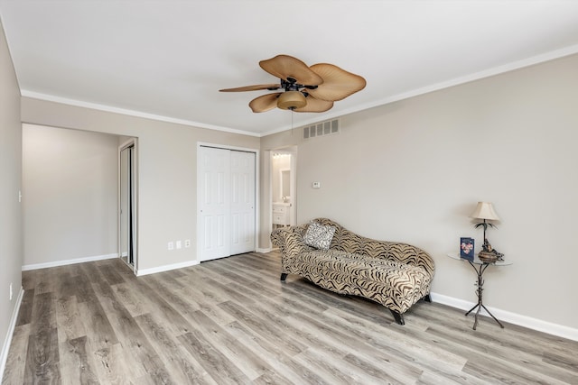 living area featuring baseboards, visible vents, crown molding, and wood finished floors