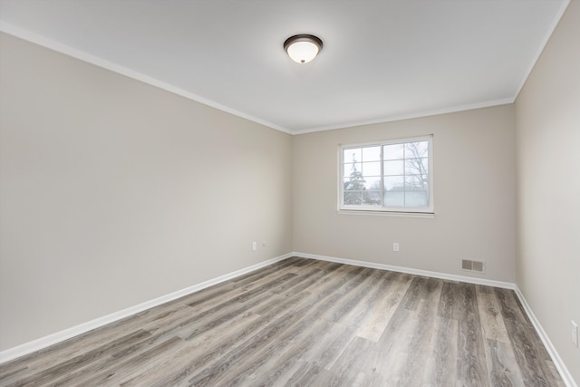 spare room featuring crown molding, wood finished floors, visible vents, and baseboards