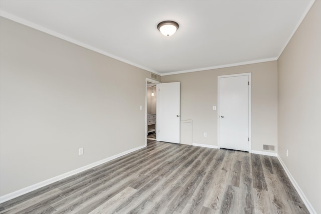 unfurnished bedroom featuring ornamental molding, light wood finished floors, visible vents, and baseboards