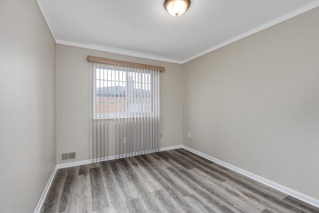 unfurnished room with ornamental molding, wood finished floors, visible vents, and baseboards