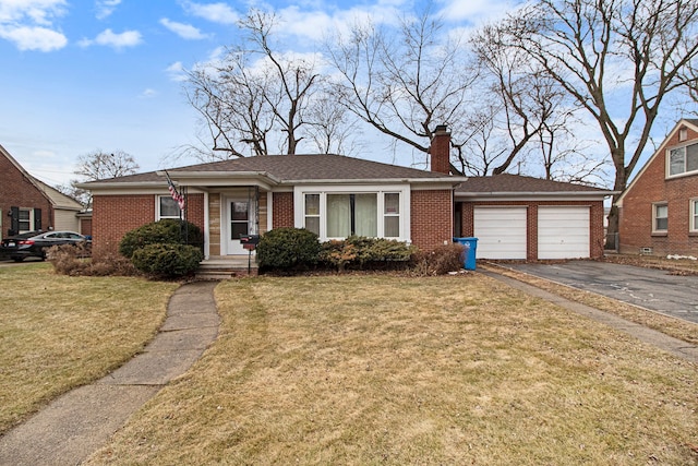 view of front of home featuring brick siding, a chimney, a front yard, a garage, and driveway