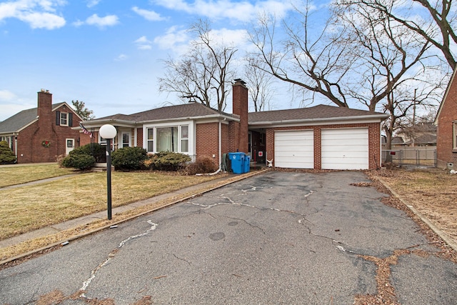 view of front of home with aphalt driveway, a garage, brick siding, a chimney, and a front yard