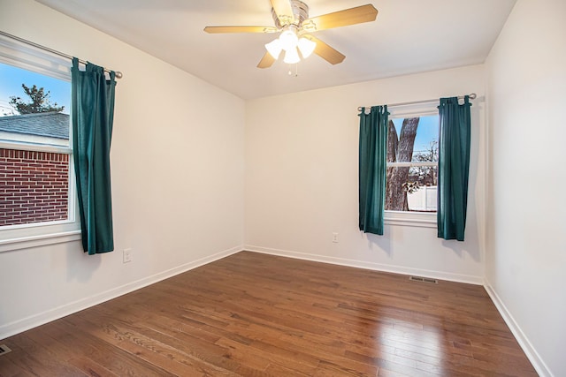 spare room with a ceiling fan, baseboards, visible vents, and hardwood / wood-style floors