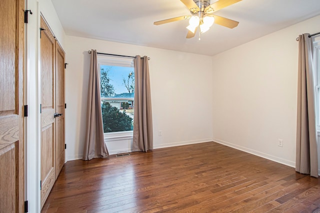 unfurnished bedroom with dark wood-style floors, visible vents, and baseboards