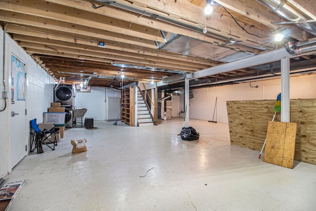 unfinished basement with stairway, stacked washer and clothes dryer, and tile patterned floors