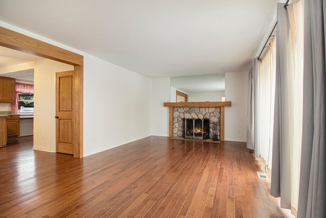 unfurnished living room featuring light wood-type flooring, visible vents, and a stone fireplace