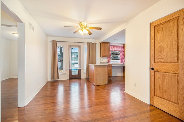 kitchen featuring visible vents, a ceiling fan, open floor plan, wood finished floors, and light countertops