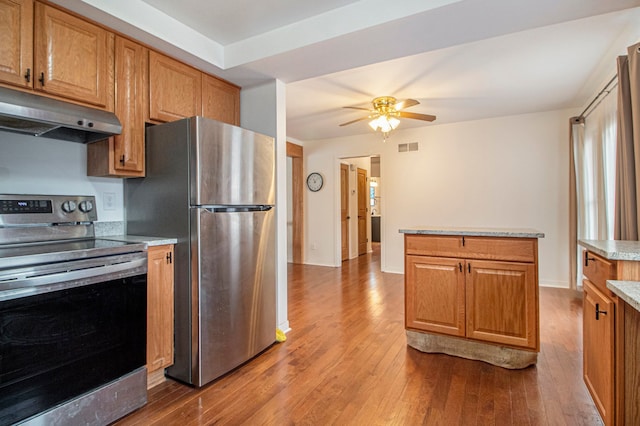 kitchen with visible vents, brown cabinetry, appliances with stainless steel finishes, hardwood / wood-style floors, and under cabinet range hood