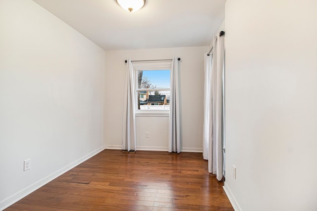 spare room featuring hardwood / wood-style floors and baseboards