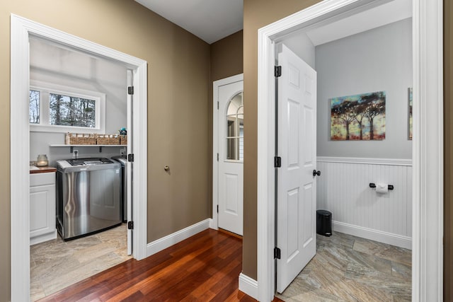 laundry area with laundry area, washer and dryer, a wainscoted wall, and wood finished floors