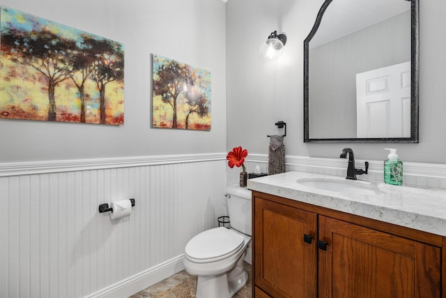 bathroom with wainscoting, vanity, and toilet