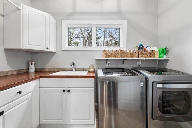 laundry area featuring washing machine and dryer, a sink, and cabinet space