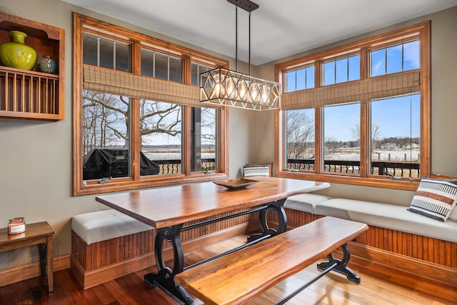 dining space with breakfast area, wood finished floors, and a notable chandelier