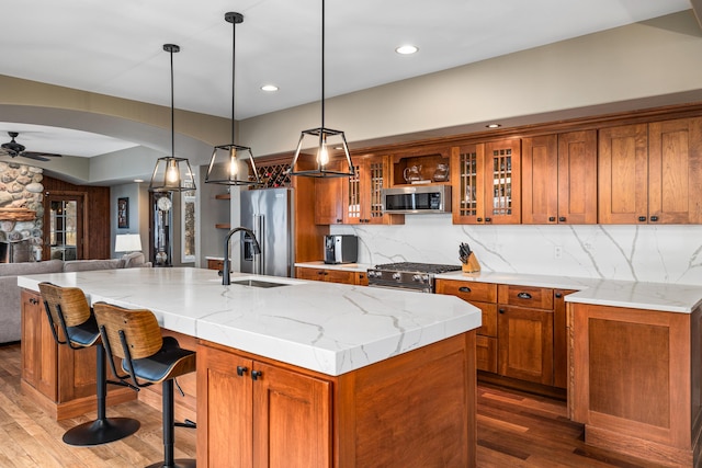 kitchen featuring a ceiling fan, brown cabinets, premium appliances, and open floor plan