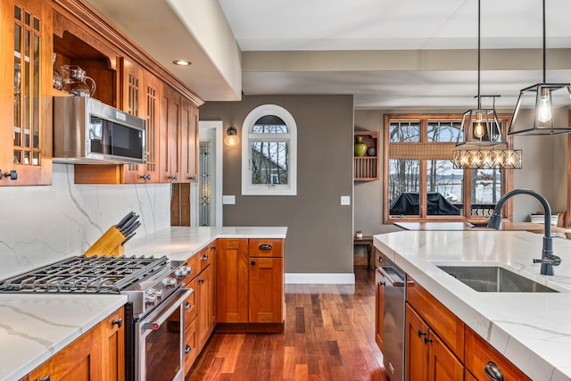 kitchen with stainless steel appliances, a sink, backsplash, brown cabinetry, and dark wood finished floors