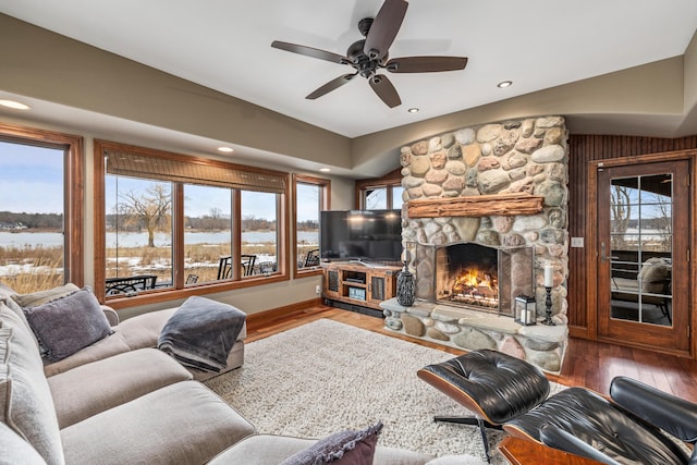 living room featuring recessed lighting, a stone fireplace, and wood finished floors