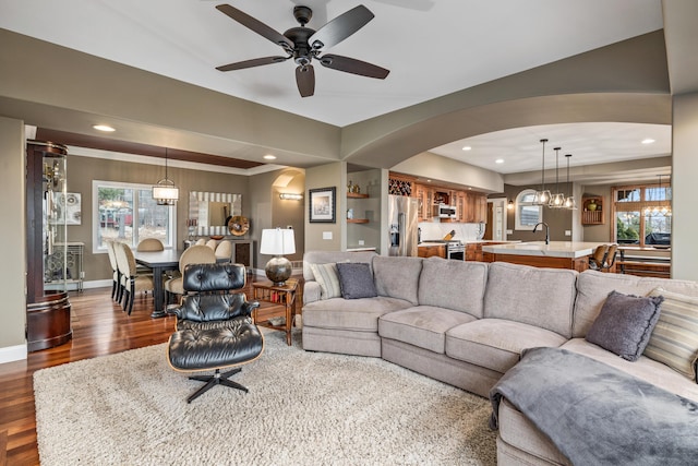 living room featuring recessed lighting, baseboards, arched walkways, wood finished floors, and ceiling fan with notable chandelier