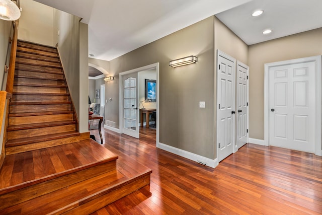 entryway featuring stairs, arched walkways, recessed lighting, baseboards, and hardwood / wood-style flooring