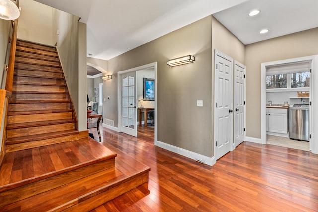 foyer with arched walkways, hardwood / wood-style flooring, recessed lighting, baseboards, and stairway