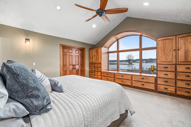 bedroom with recessed lighting, light carpet, vaulted ceiling, and a water view