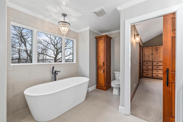 full bath with toilet, a notable chandelier, visible vents, ornamental molding, and a soaking tub