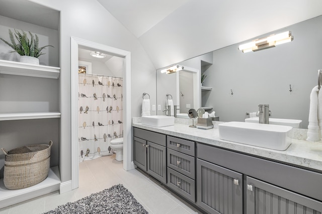 bathroom with vaulted ceiling, double vanity, a sink, and toilet