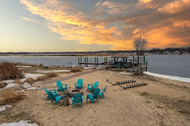 property view of water with an outdoor fire pit and a dock