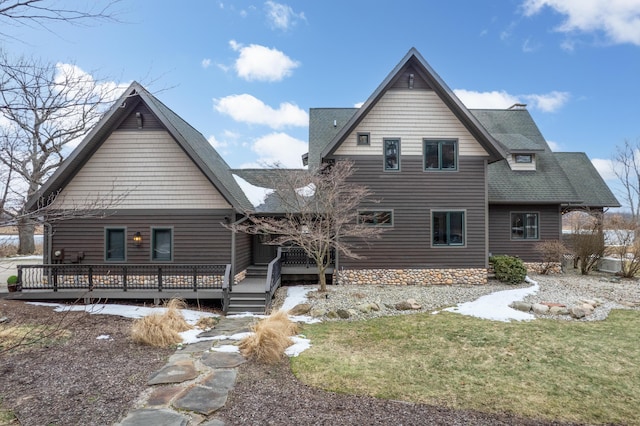 rear view of property featuring a shingled roof, a lawn, and a wooden deck