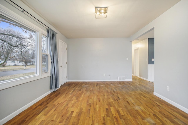 empty room with light wood-style flooring, visible vents, and baseboards