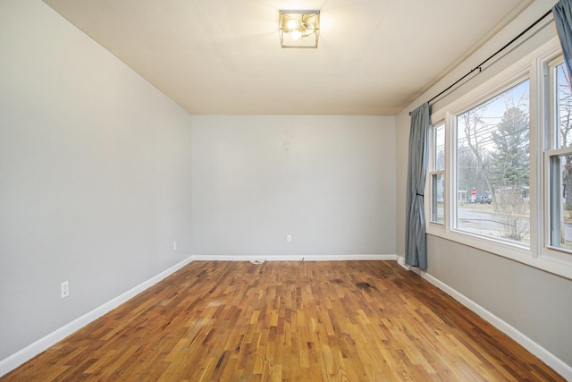 unfurnished room with baseboards and wood finished floors