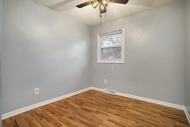 empty room featuring ceiling fan, wood finished floors, visible vents, and baseboards