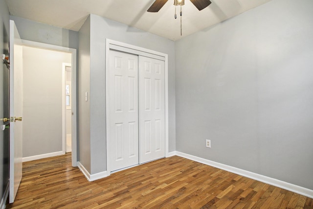 unfurnished bedroom featuring ceiling fan, a closet, baseboards, and wood finished floors