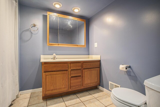 bathroom with toilet, vanity, baseboards, visible vents, and tile patterned floors