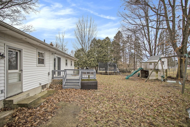 view of yard featuring entry steps, a playground, fence, a wooden deck, and a trampoline