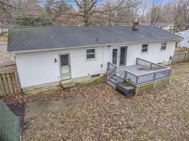 rear view of property with entry steps, a shingled roof, a chimney, and fence