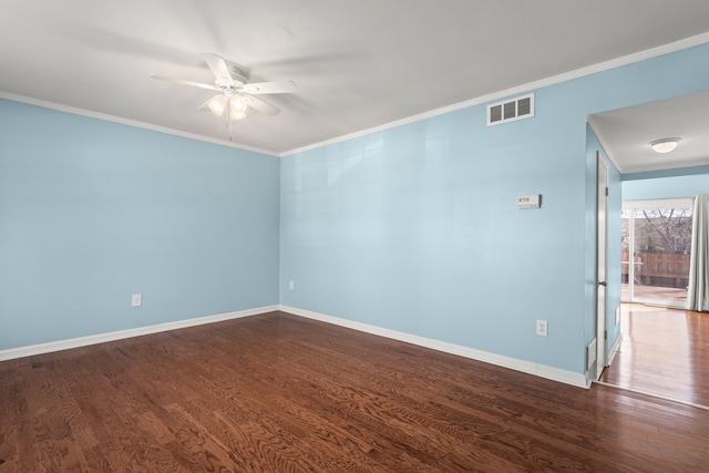 spare room with dark wood-style flooring, visible vents, ornamental molding, a ceiling fan, and baseboards