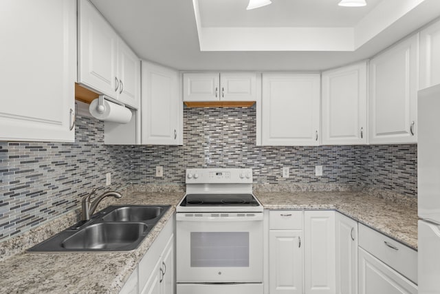 kitchen featuring white appliances, a sink, white cabinetry, light countertops, and backsplash