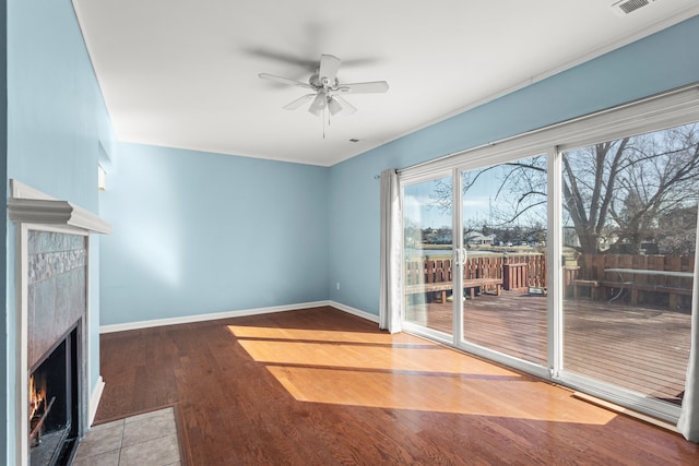 unfurnished living room featuring a ceiling fan, a fireplace, baseboards, and wood finished floors