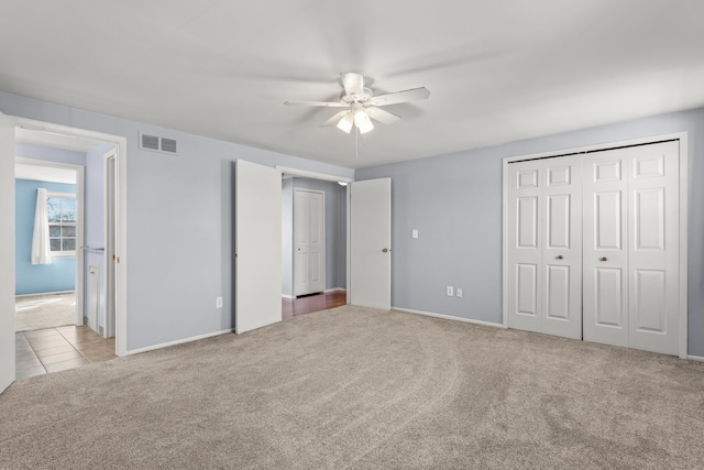 unfurnished bedroom featuring a closet, visible vents, a ceiling fan, carpet flooring, and tile patterned flooring