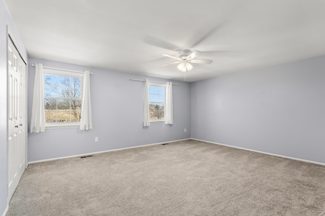 empty room featuring baseboards, ceiling fan, visible vents, and carpet flooring