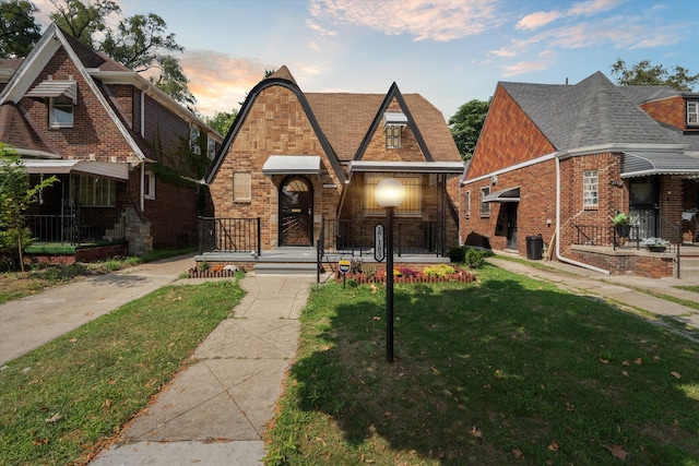 tudor-style house featuring a yard and brick siding