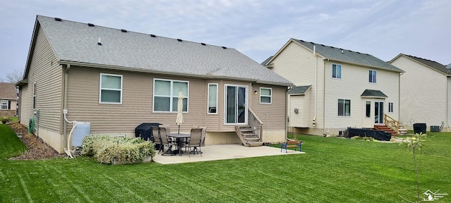 rear view of property featuring a shingled roof, entry steps, a patio area, and a lawn