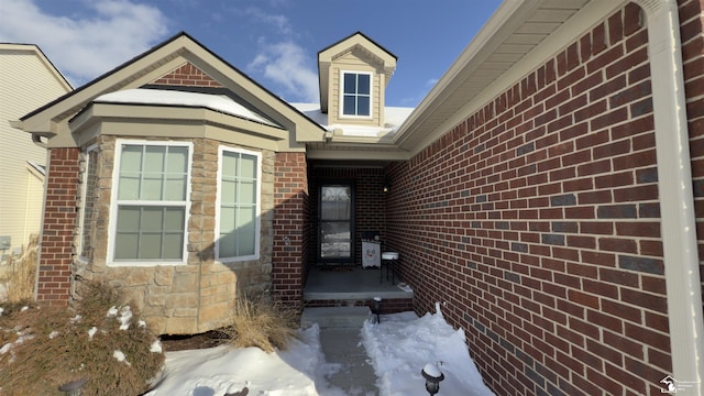 snow covered property entrance with brick siding