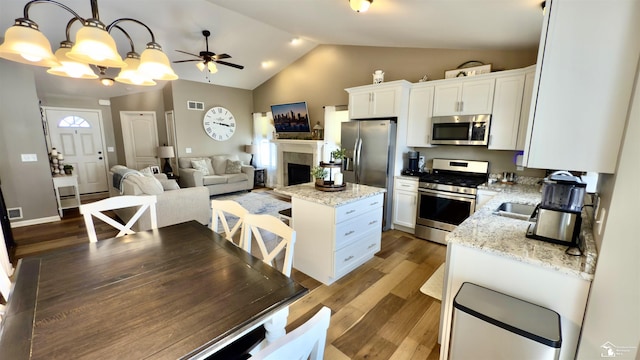 kitchen featuring a center island, stainless steel appliances, white cabinets, vaulted ceiling, and wood finished floors